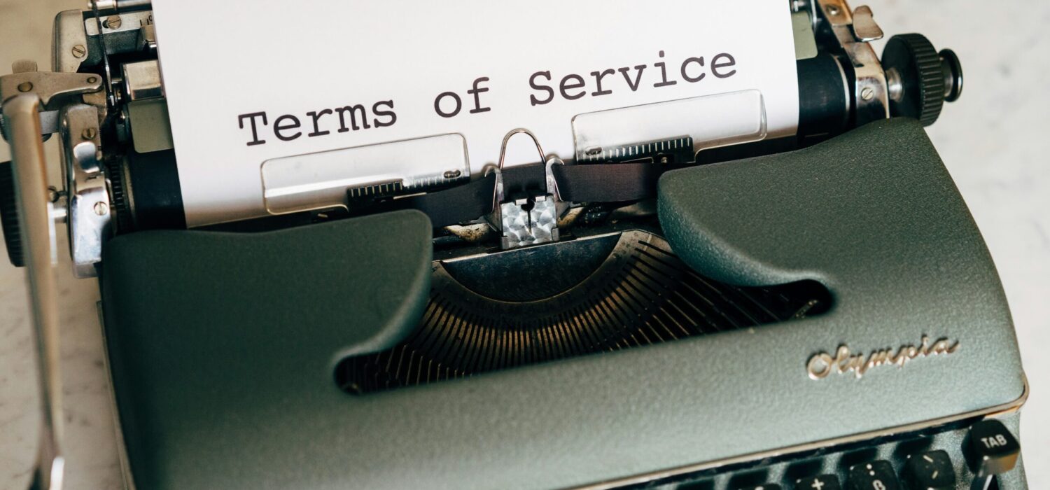 "Terms of Service" written in black ink on a white paper coming out of a typewritter, representing legal documentation and agreements.